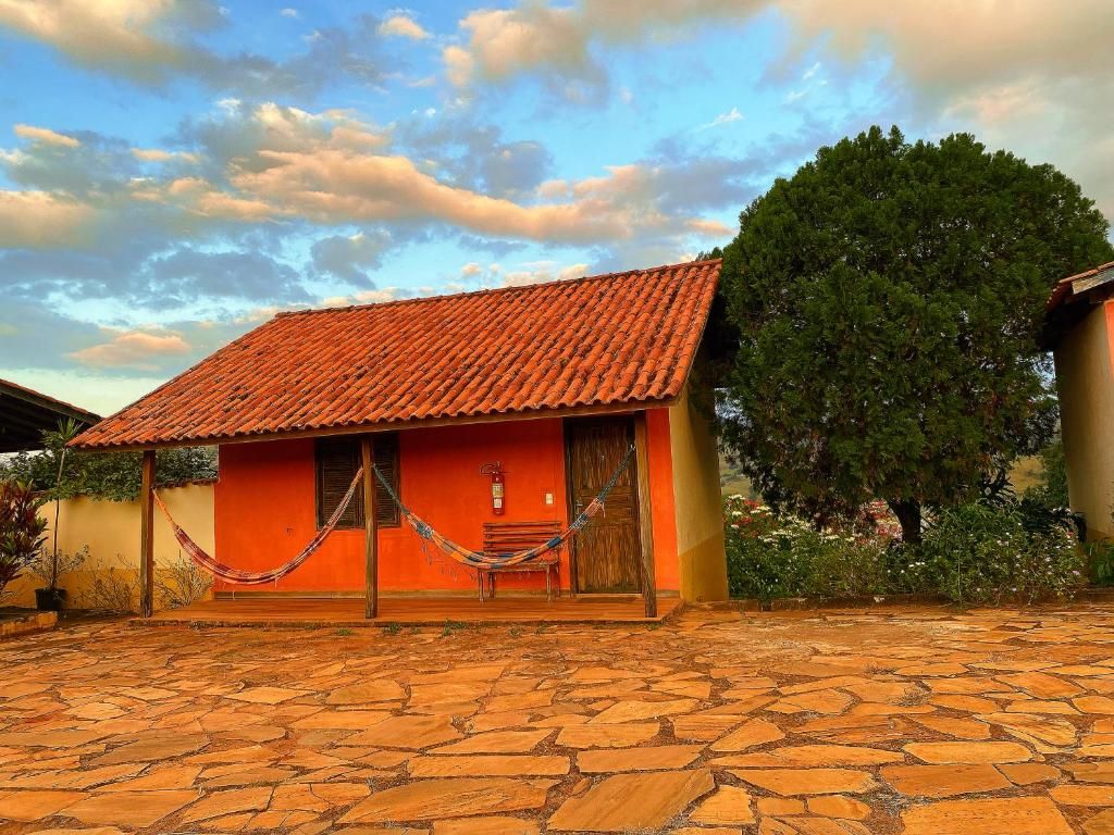 Casa de paredes alaranjadas com redes na varanda e pátio de pedra